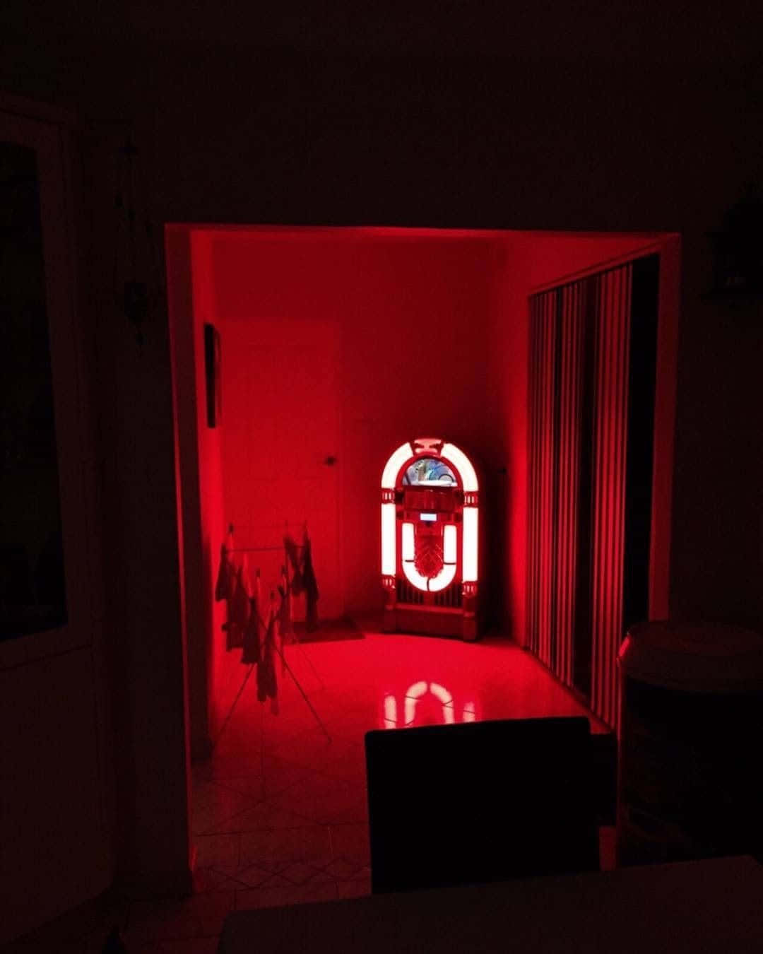 Et rødt lys skinner på en jukebox. Wallpaper