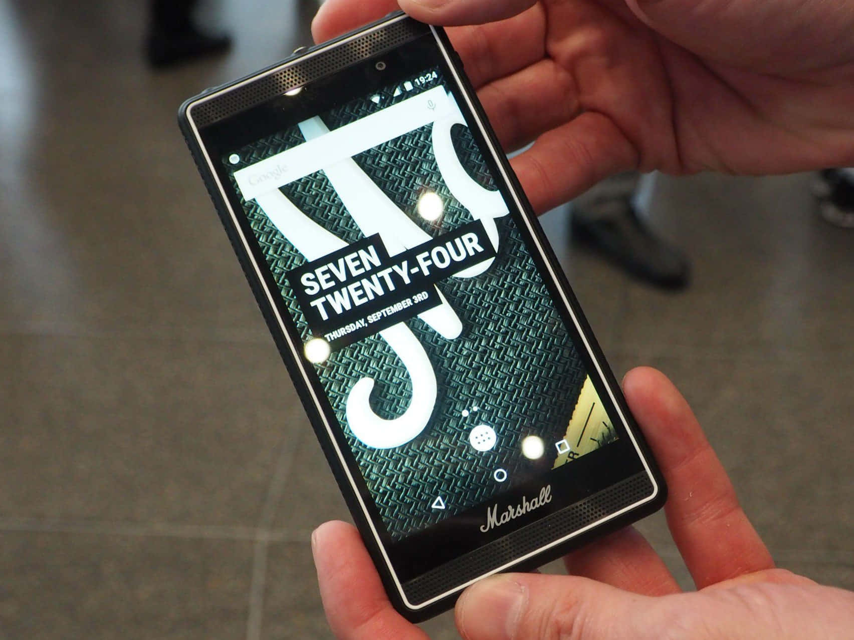 A Person Holding A Smartphone With The Word 'seven' On It