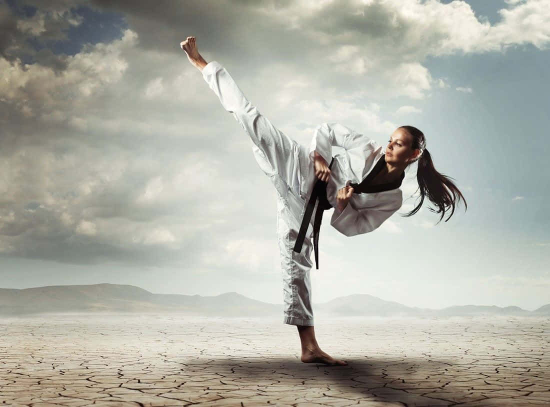 Caption: Two martial artists in their uniforms showcasing a high kick during training Wallpaper
