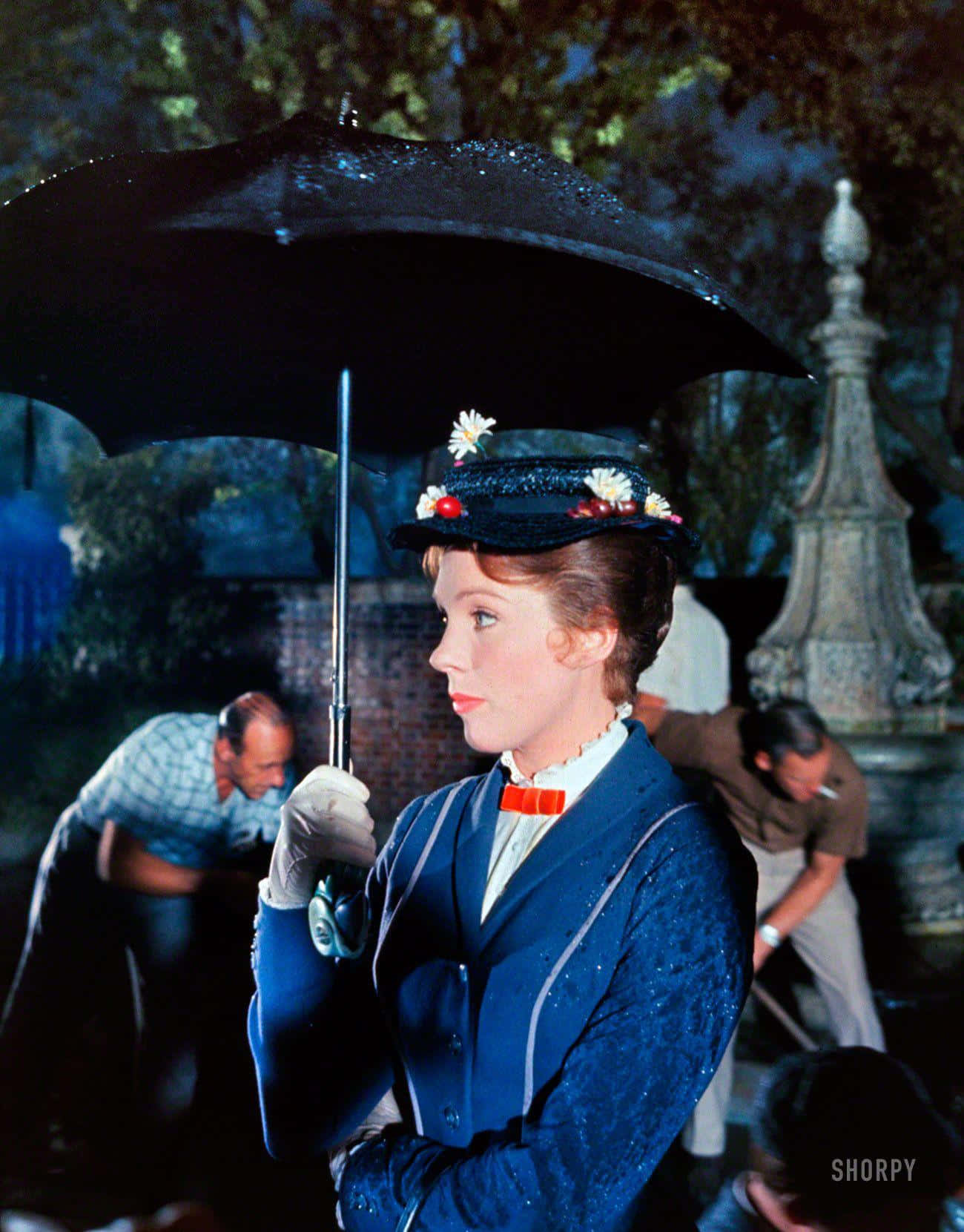 Mary Poppins soaring through the sky with her umbrella Wallpaper