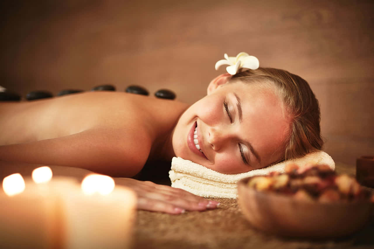 A Woman Smiling While Getting A Hot Stone Massage Wallpaper