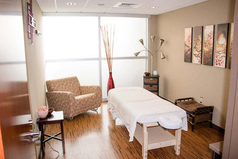 A Massage Room With A Massage Table And Chairs