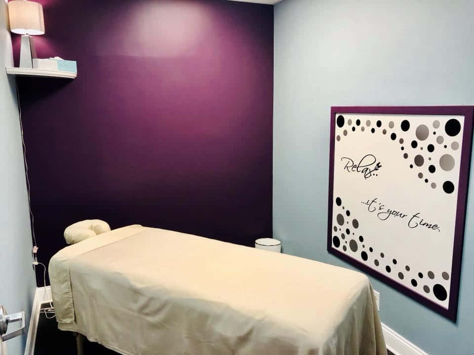 A Massage Room With Purple Walls And A Sign