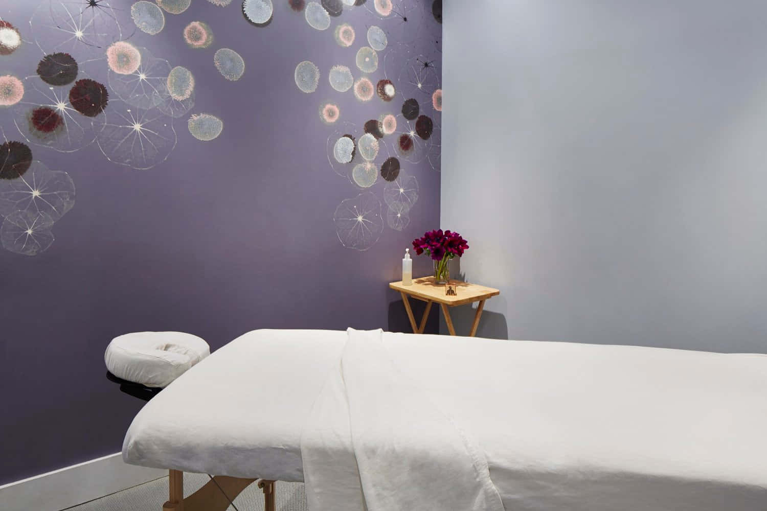 A Massage Room With Purple Walls And A White Bed