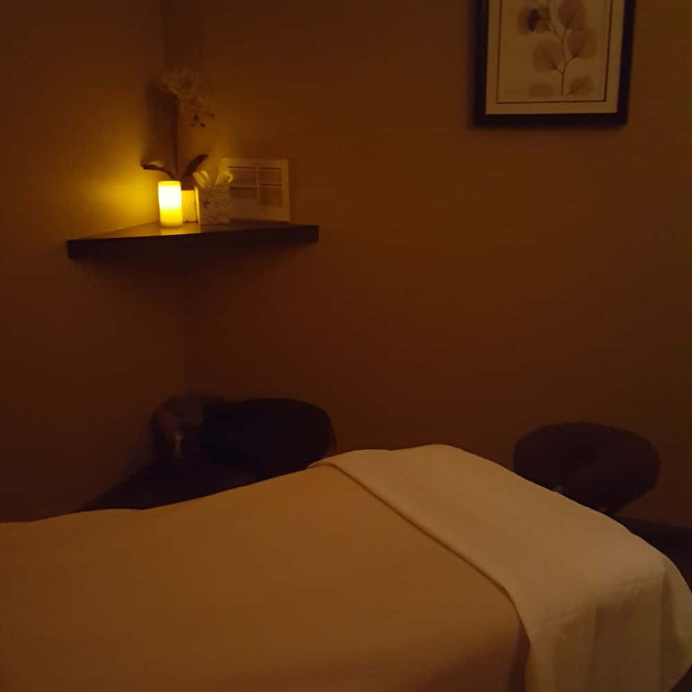 A Massage Room With A Candle And A Bed