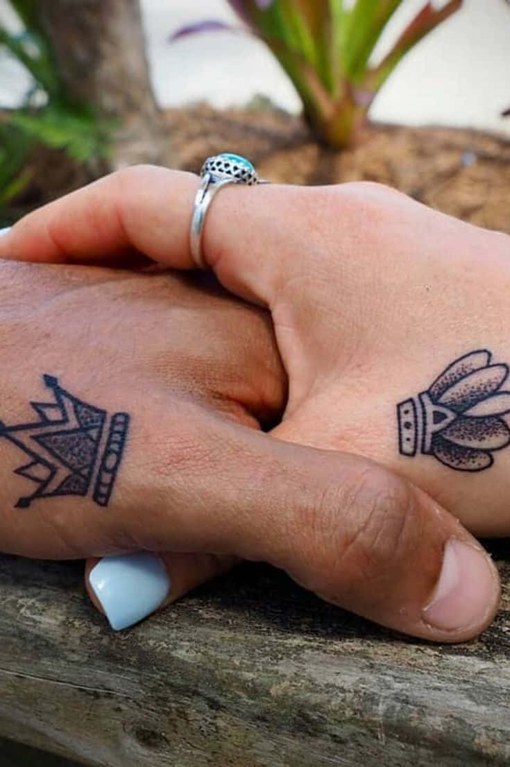 Two People Holding Hands With A Crown Tattoo