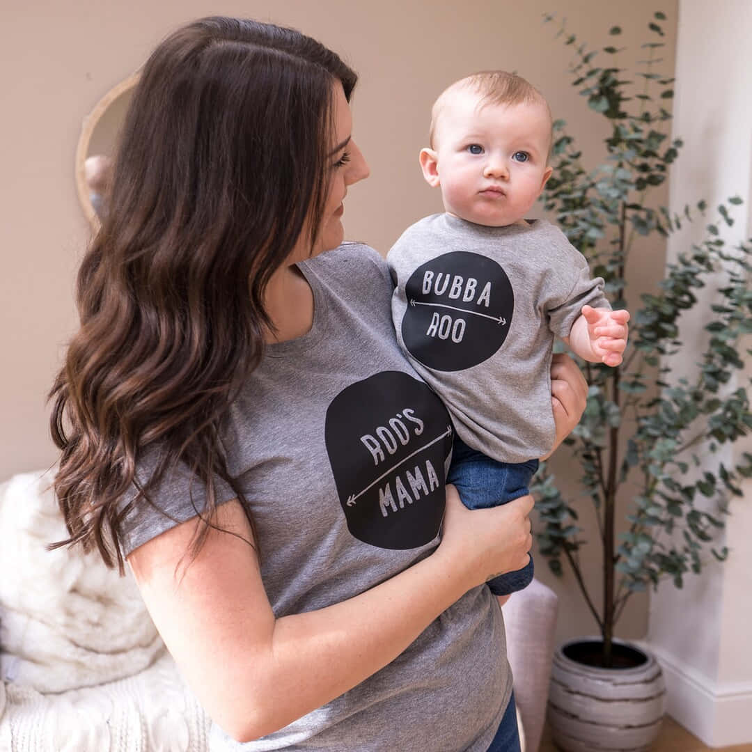 A Woman Holding A Baby Wearing A Grey Shirt That Says Dotty Dotty Mama