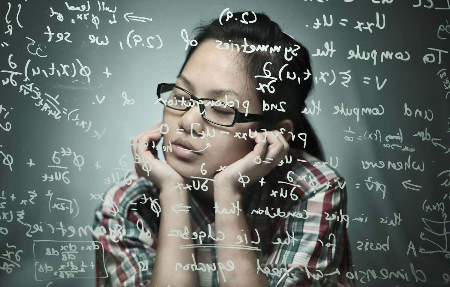 En kvinde med sine hænder på hendes hoved, der kigger på en væg med matematiske ligninger.