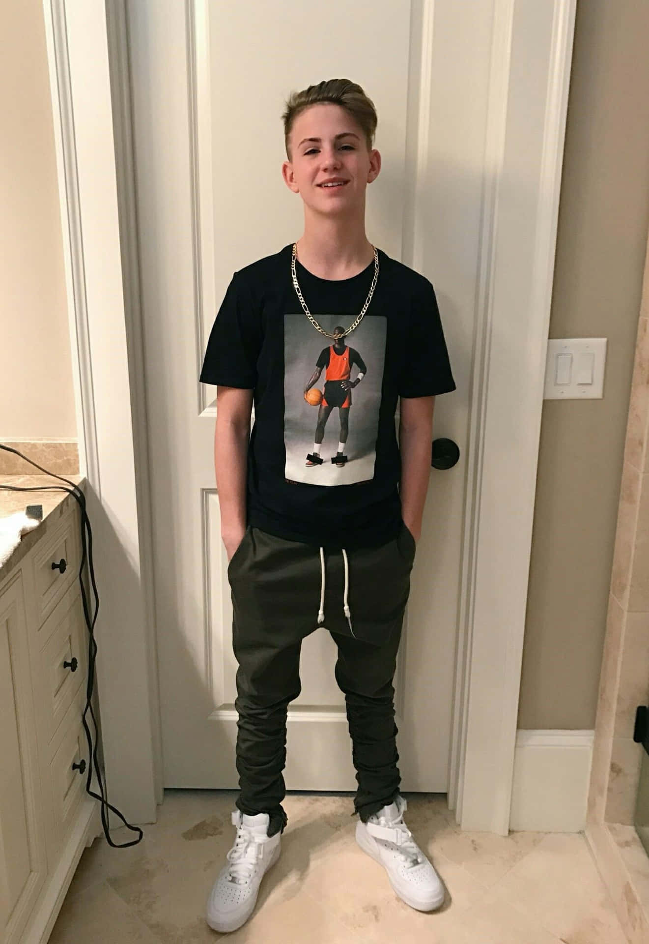 En ung mand står foran et badeværelse med en t-shirt Wallpaper
