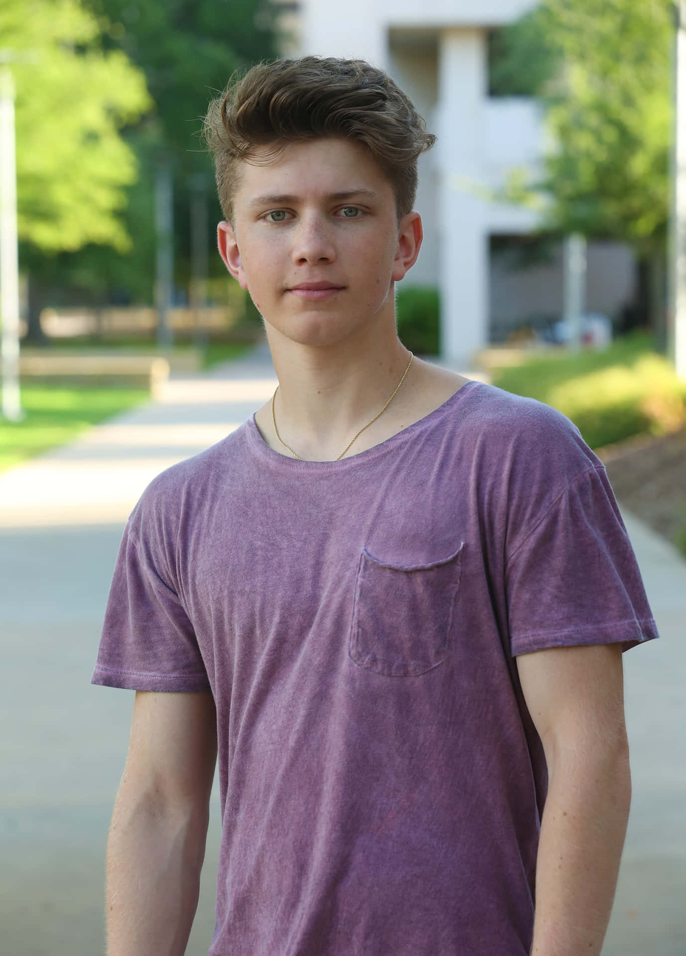 En ung mand står på fortovet med et skateboard. Wallpaper