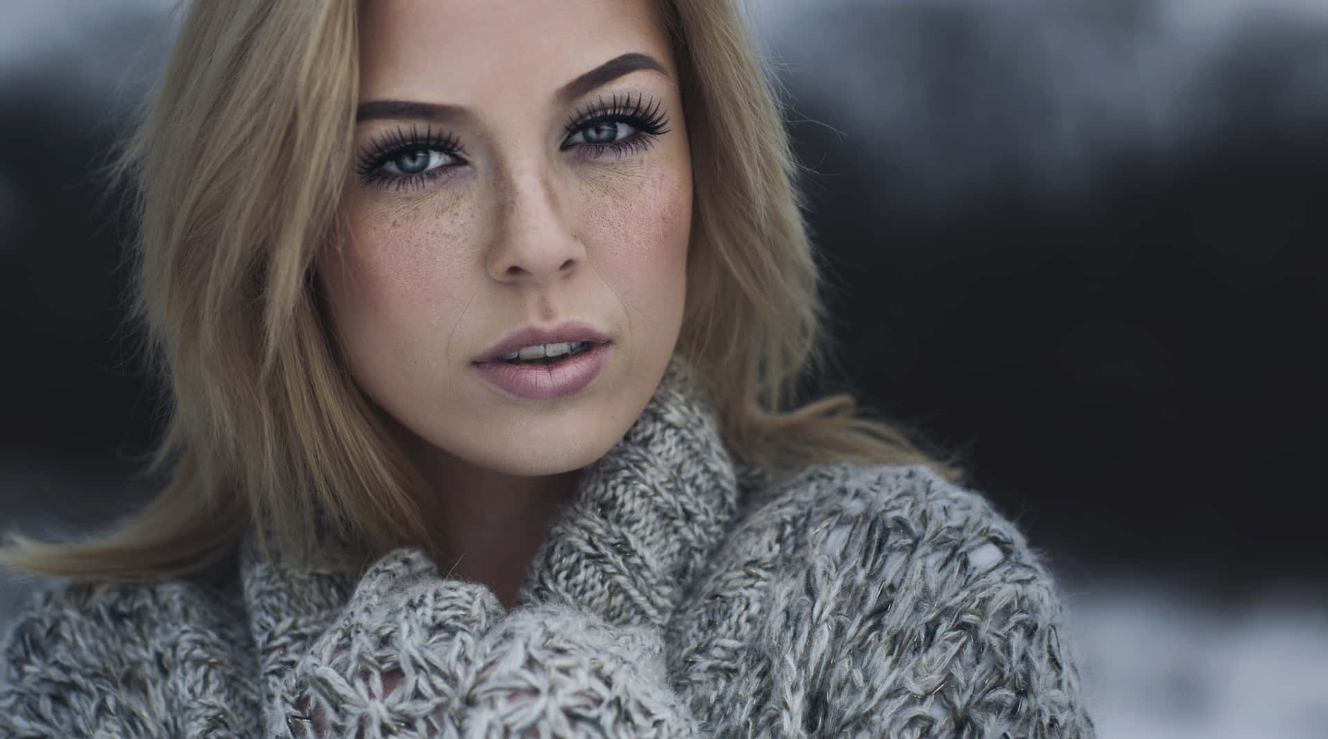 Download A Beautiful Woman In A Sweater Posing In The Snow | Wallpapers.com