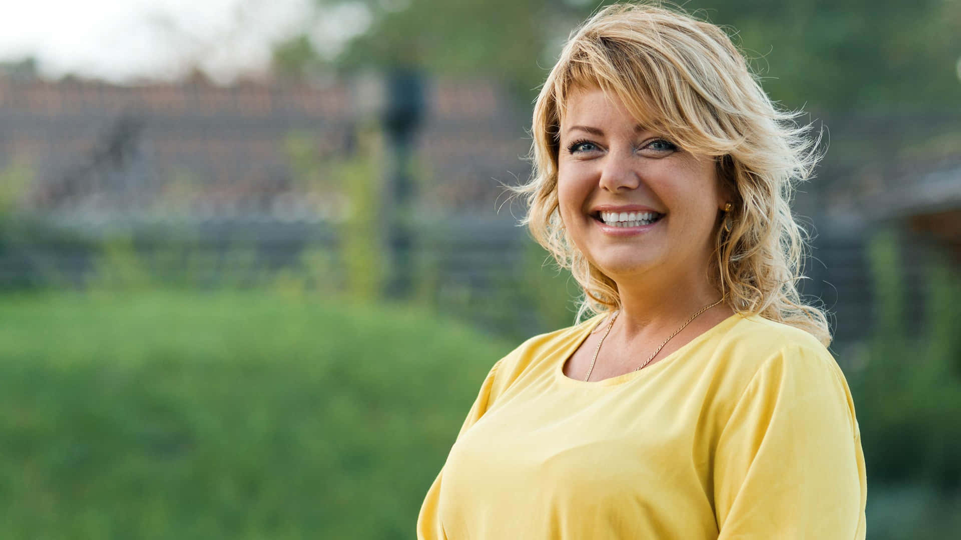 En kvinde i en gul skjorte smiler