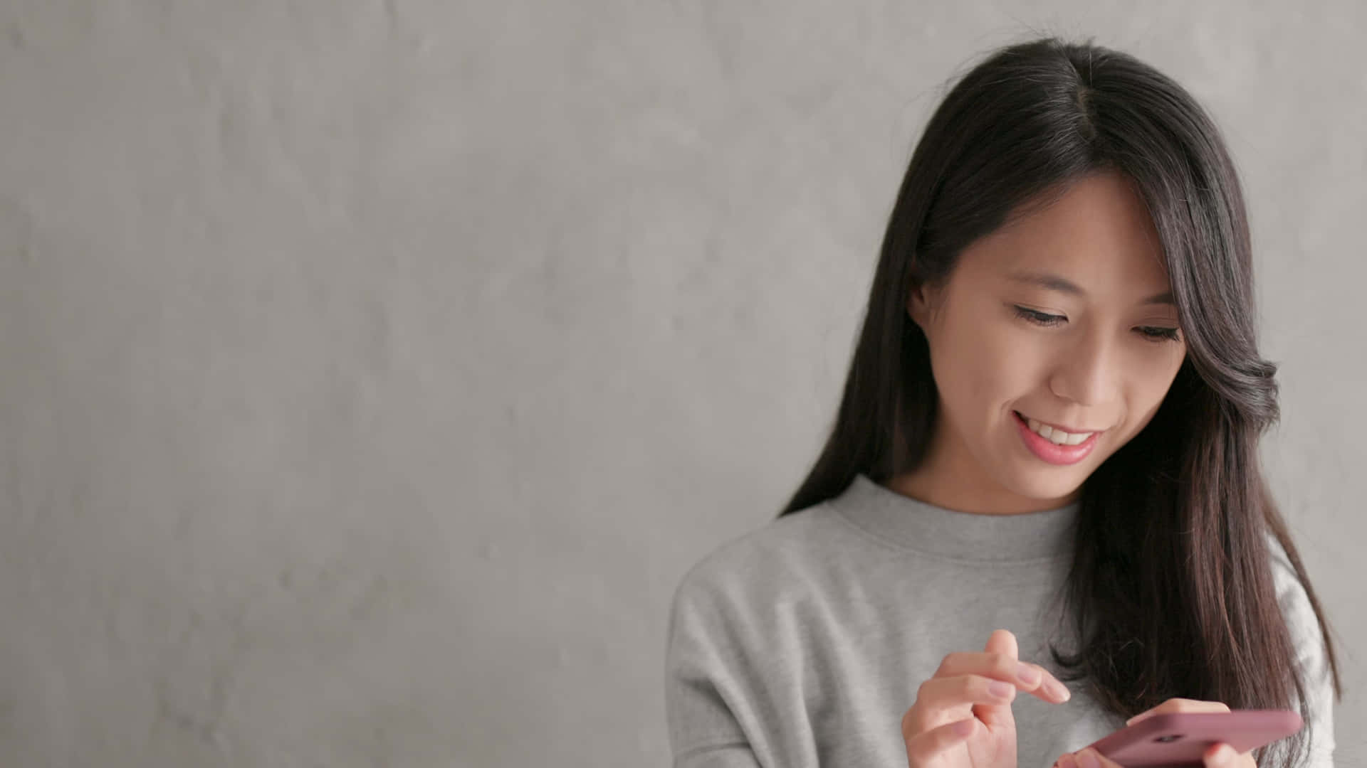 En ung asiatisk kvinde bruger hendes telefon