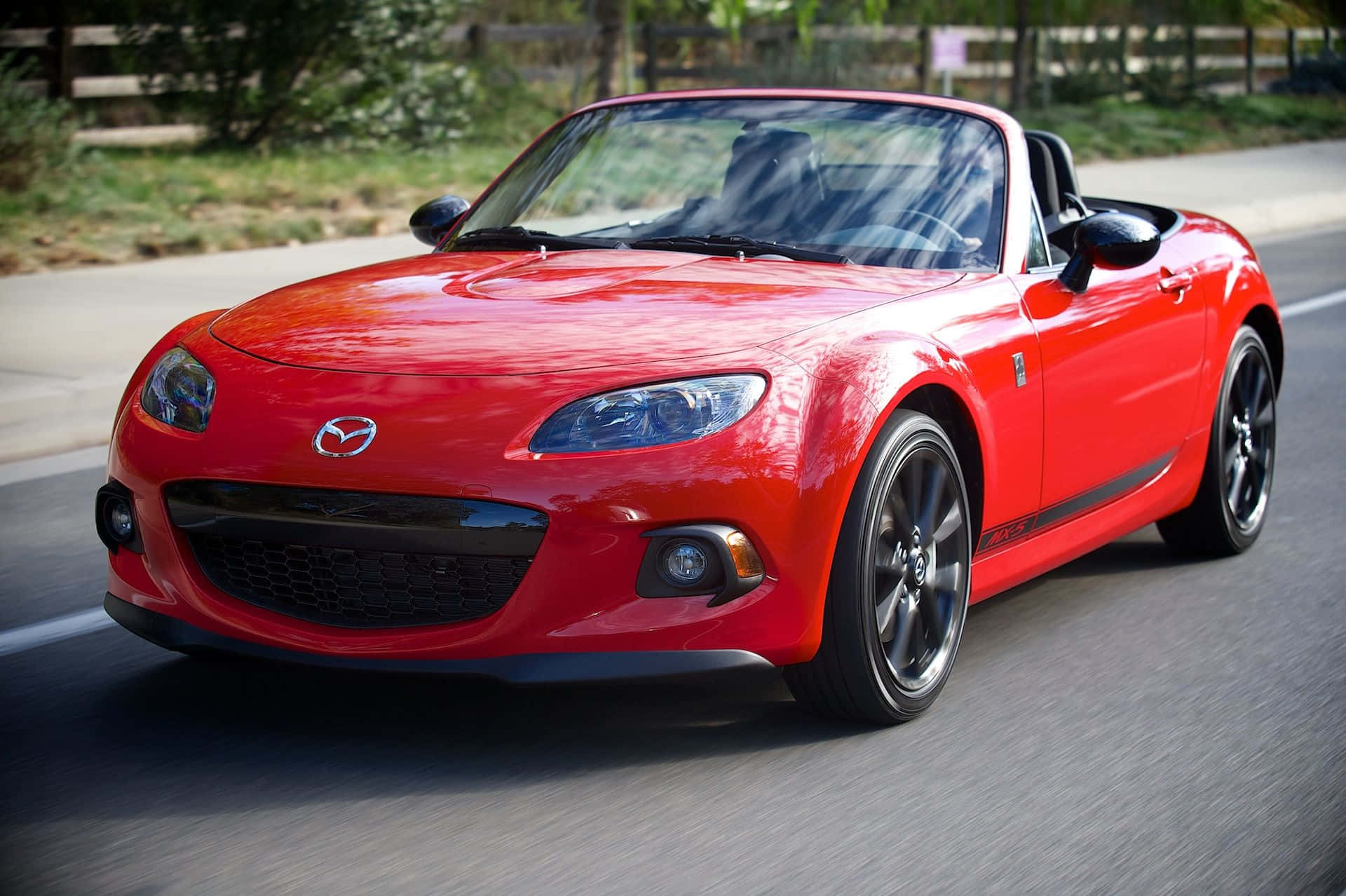 A Red Mazda Mx-5 Roadster Driving Down The Road Wallpaper