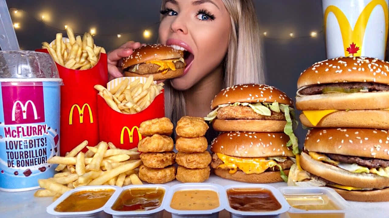 A Woman Is Eating A Mcdonald's Burger With Fries