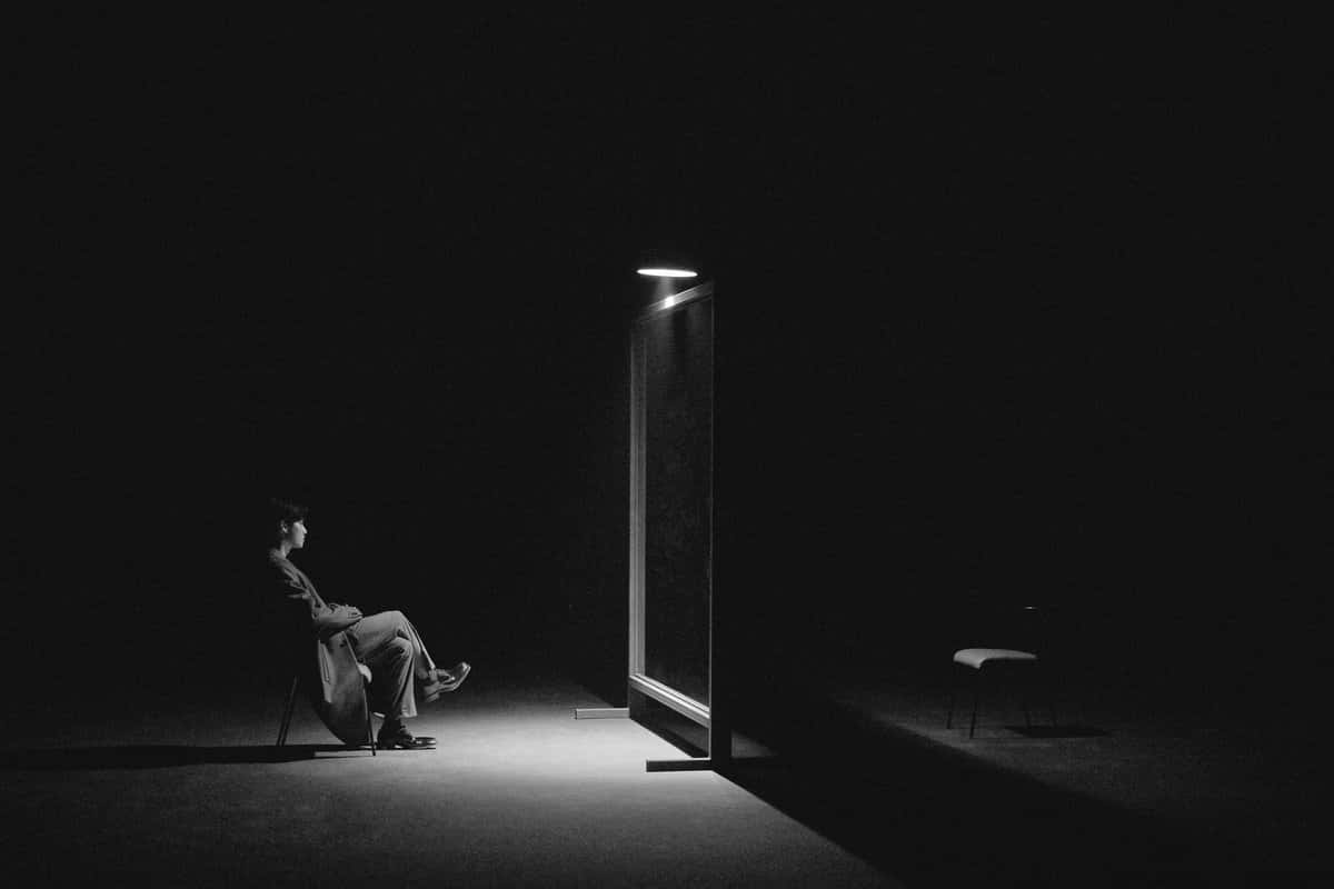 A Person Sitting In A Chair In The Dark