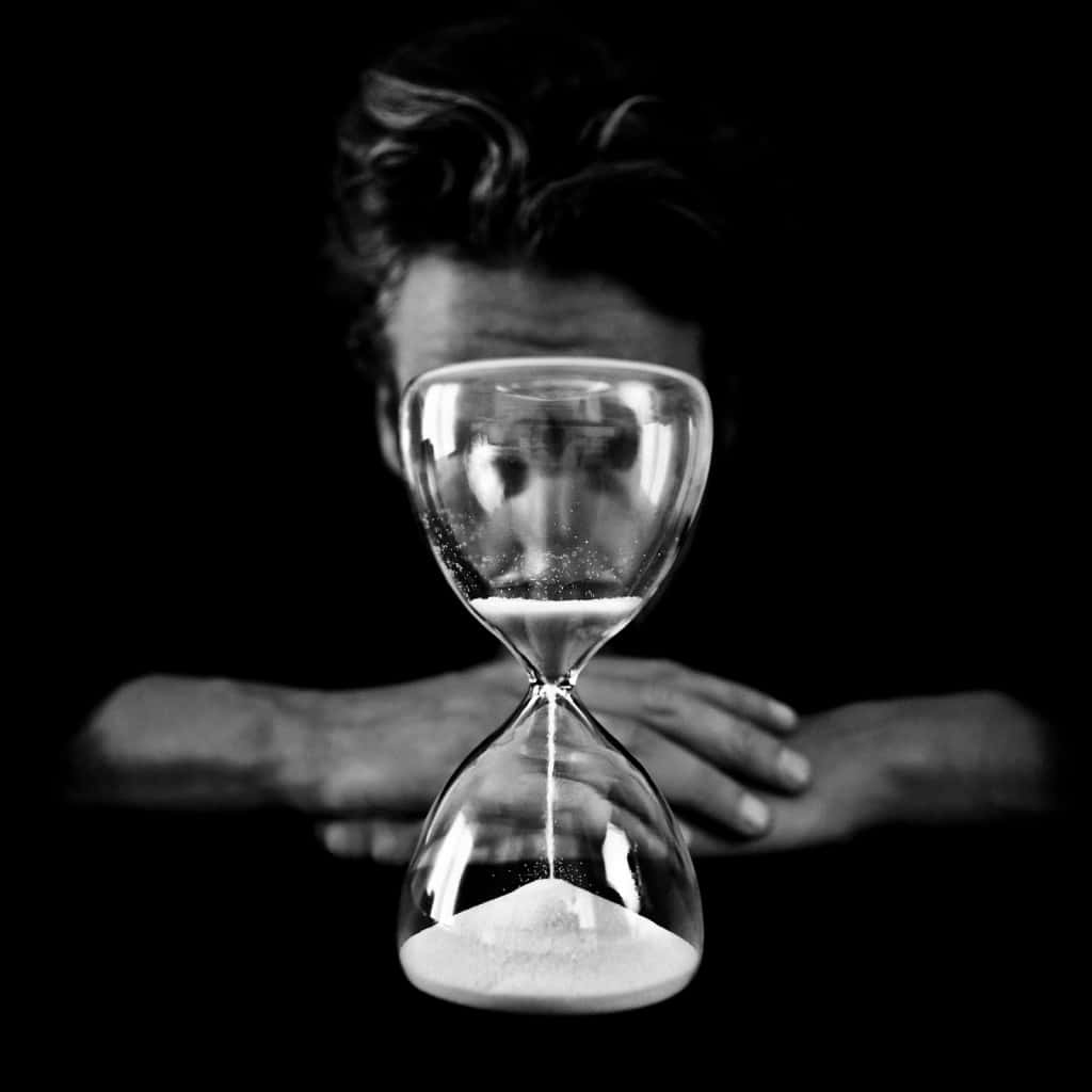 A Man Is Looking At A Sand Hourglass