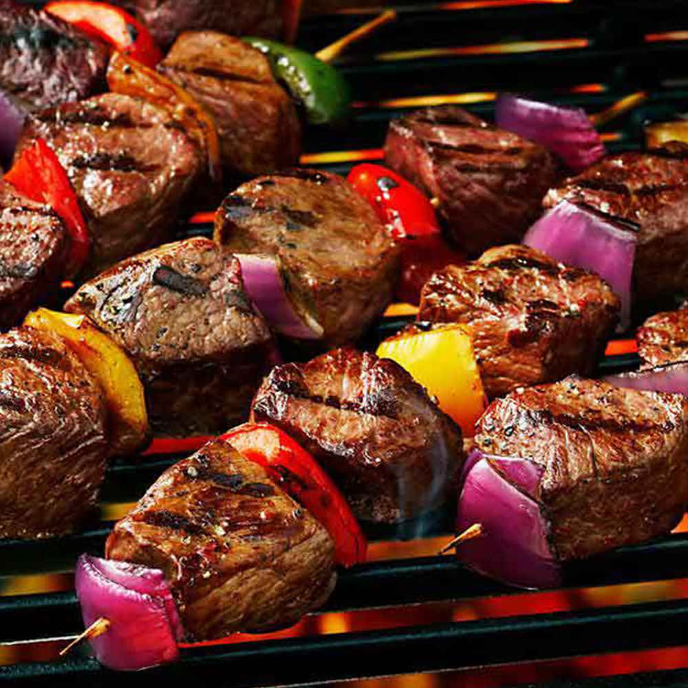 A Grill With Steak Skewers And Vegetables On It