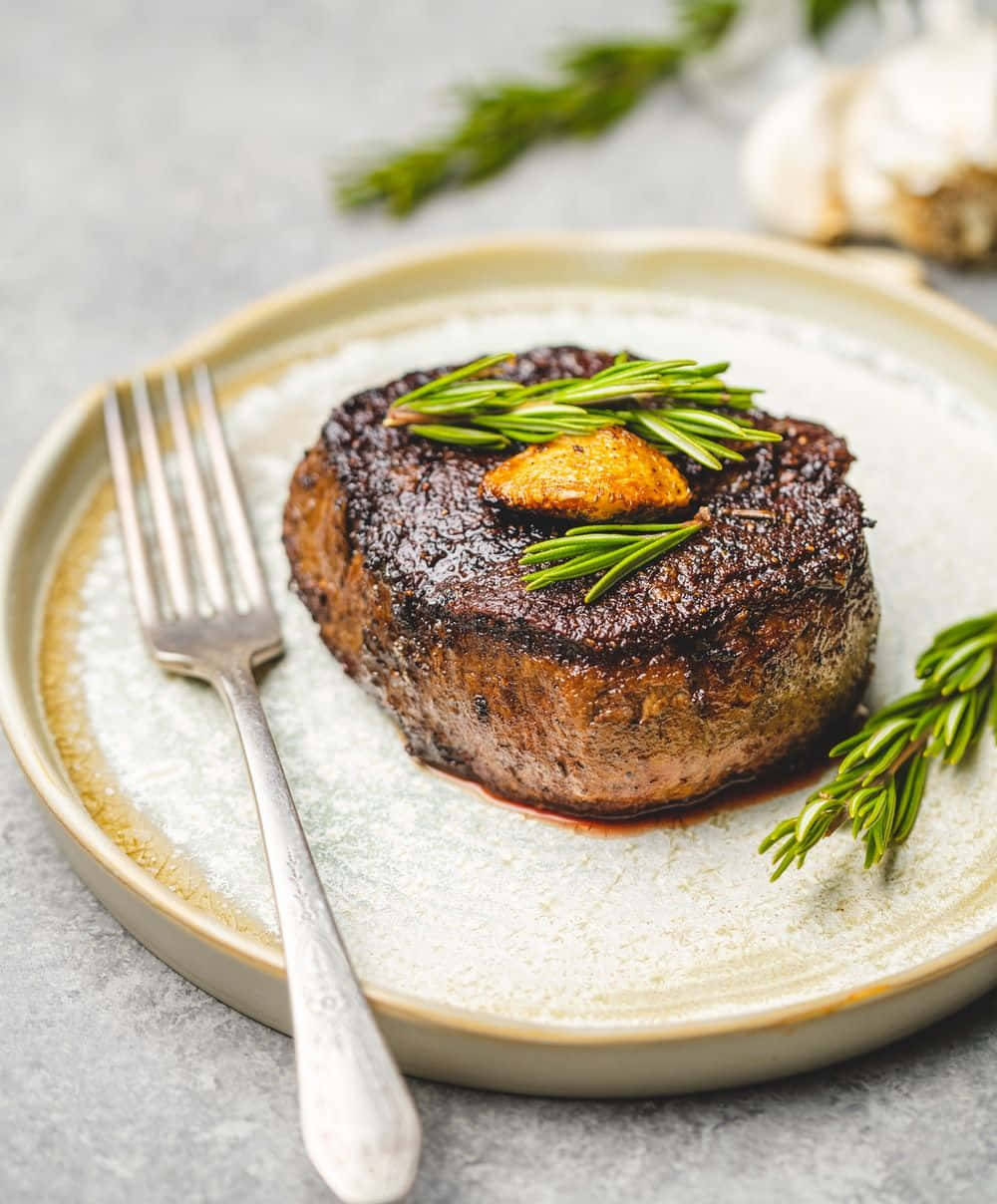 A Steak With Rosemary On A Plate