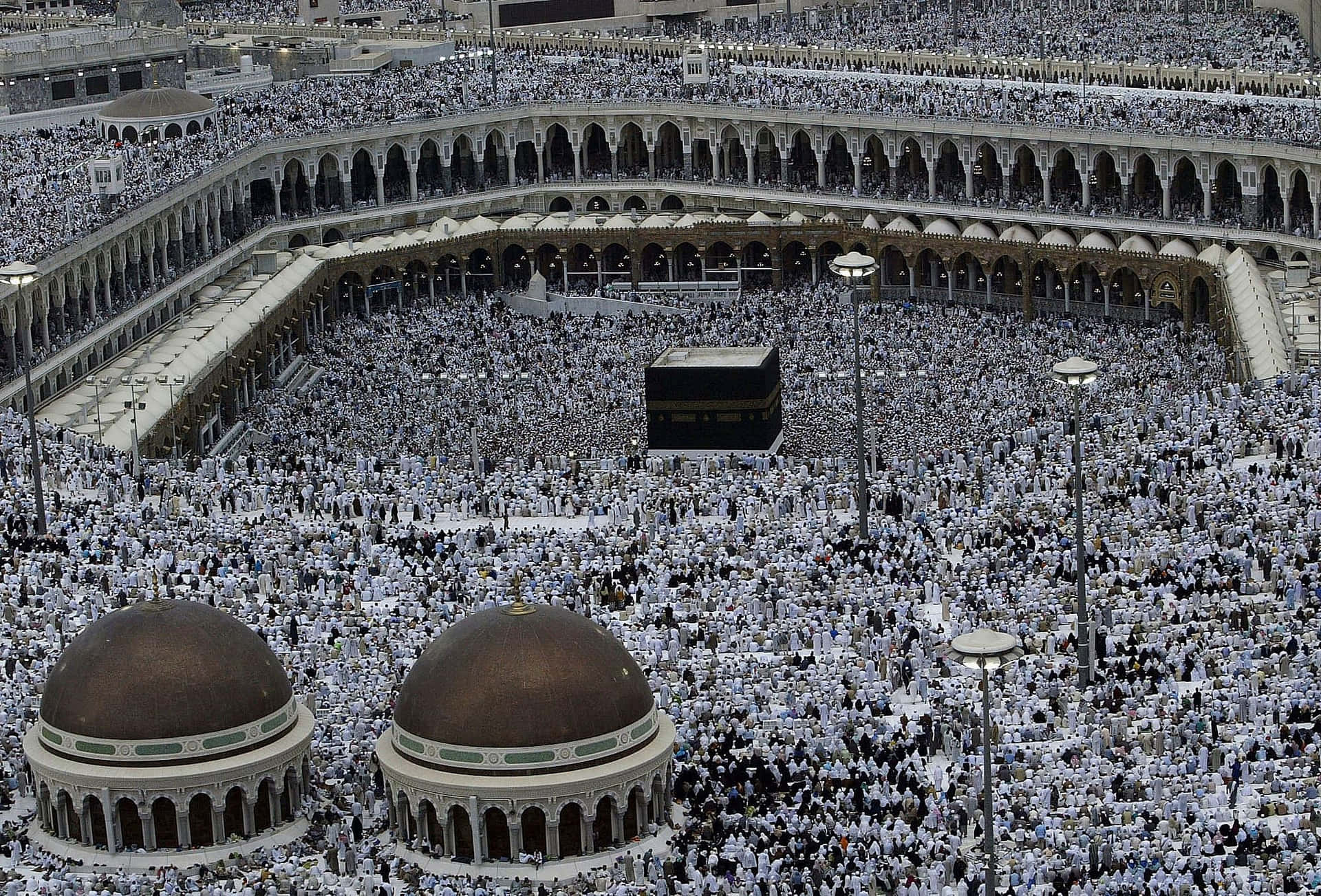 A Large Group Of People Are Standing Around A Kaaba