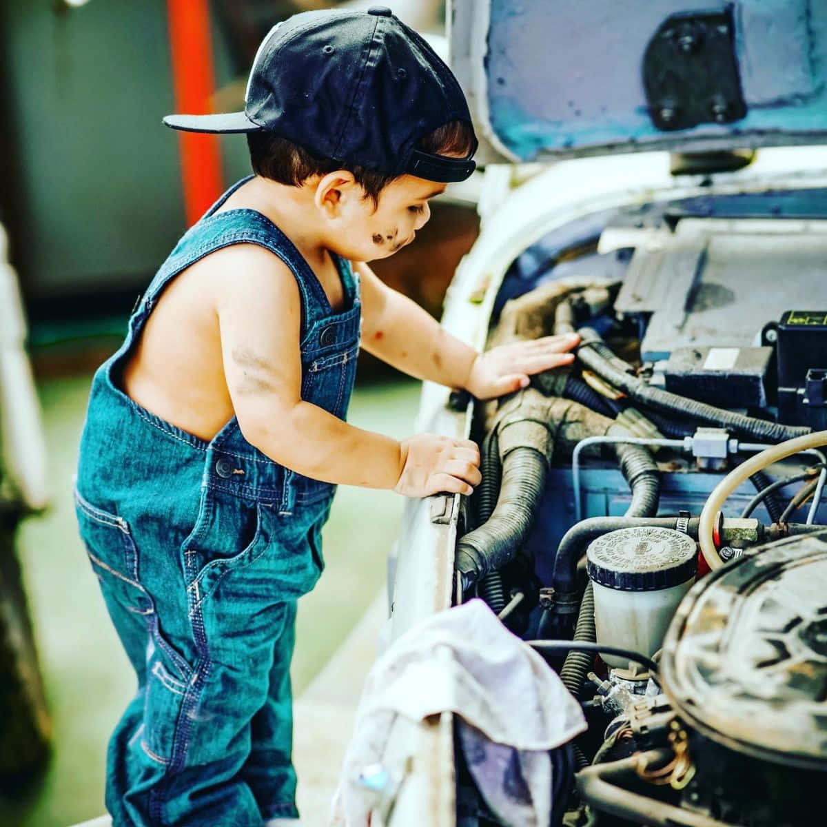 A Young Boy Is Looking At The Hood Of A Car