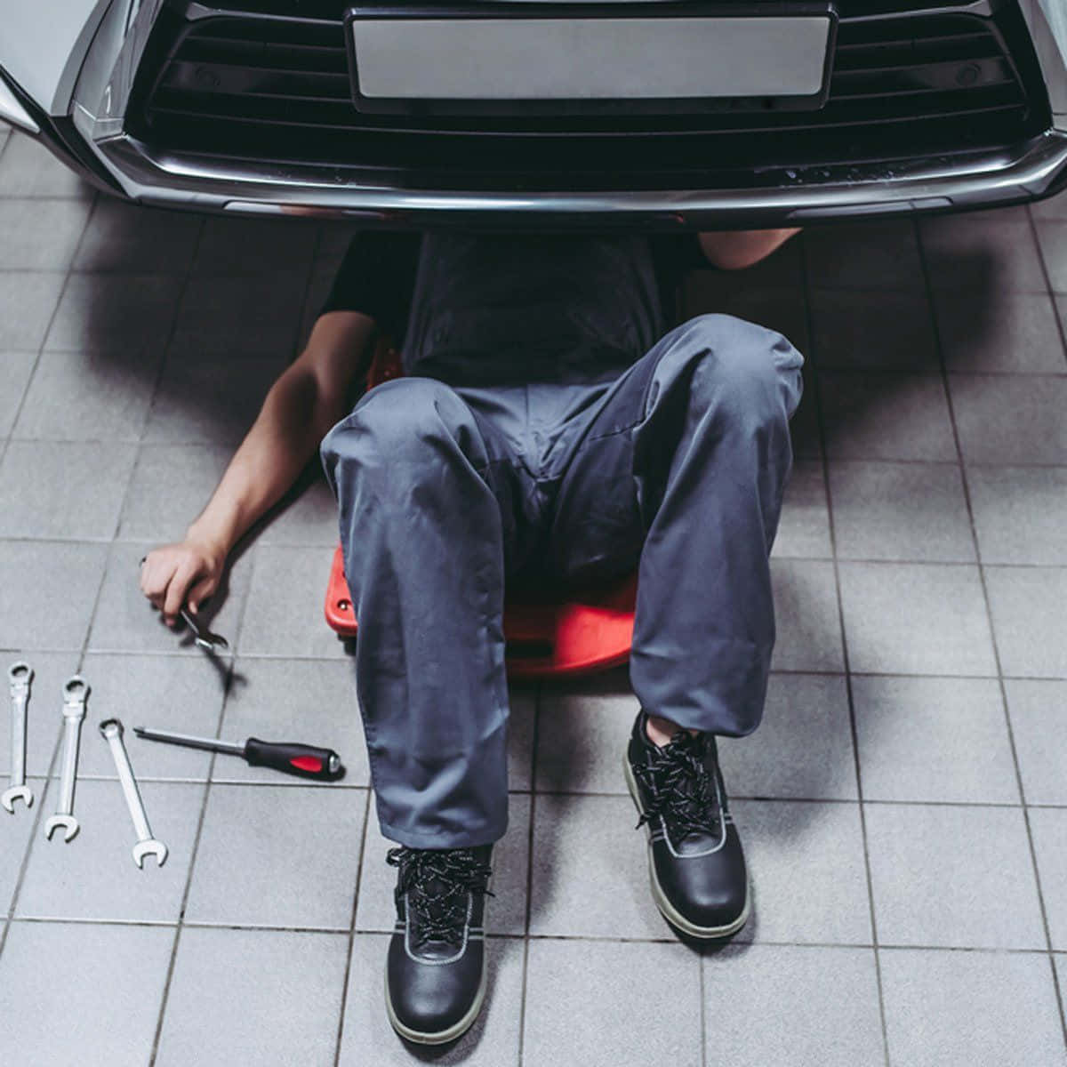 A Mechanic Is Laying On The Floor Of A Car Repair Shop