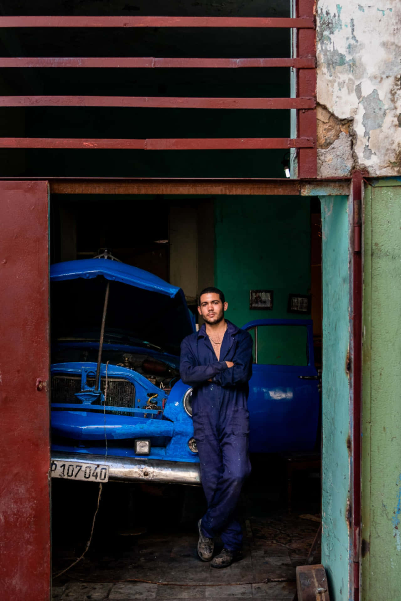 A Man Standing In Front Of A Blue Car