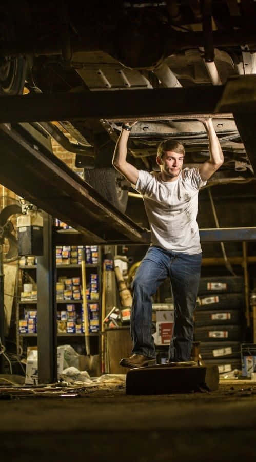 Enman Står Under En Bil I Ett Garage