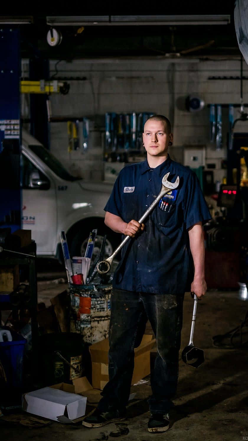A Man Standing In A Garage Holding A Wrench