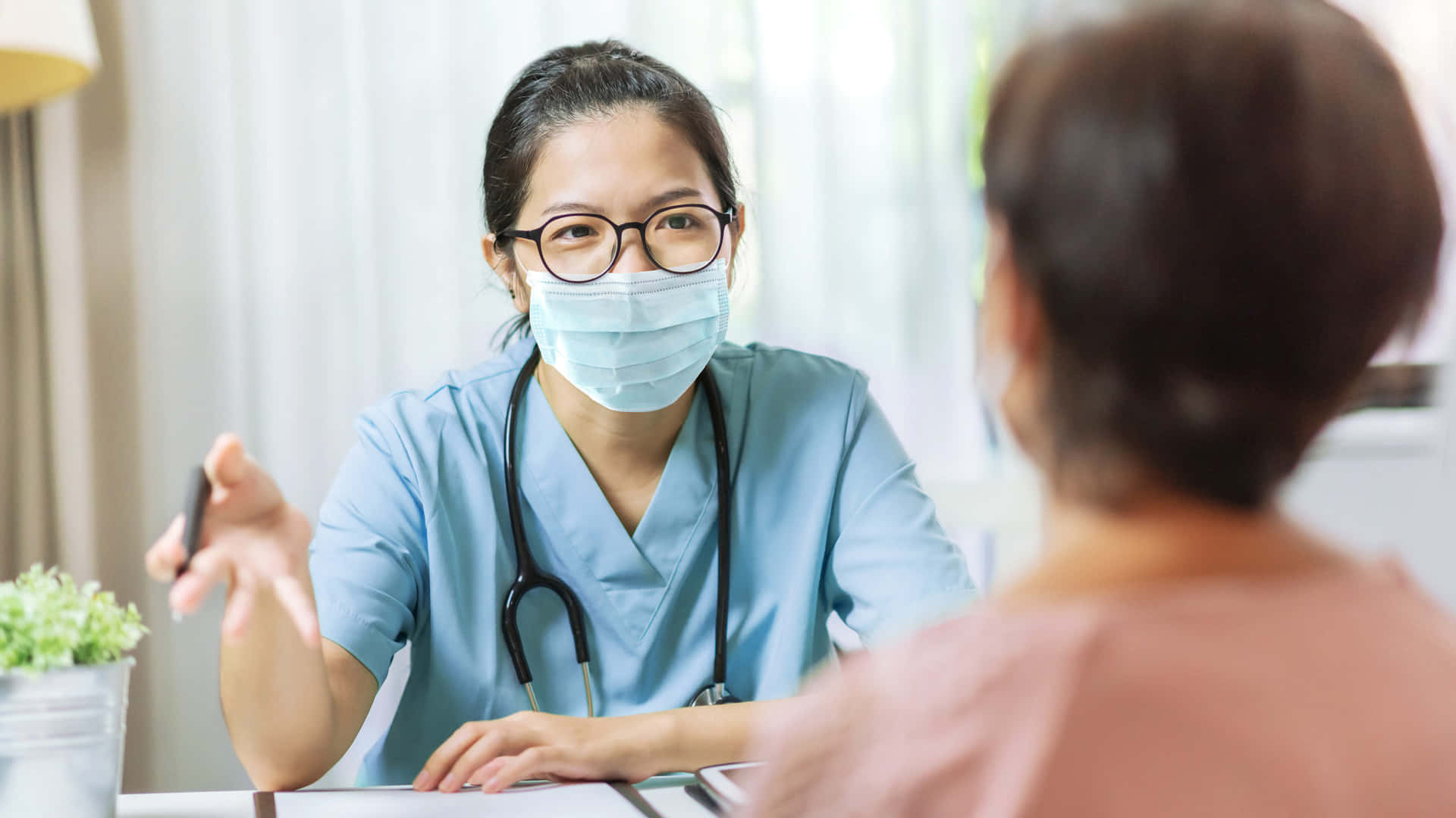 A Woman Wearing A Mask Is Talking To A Patient