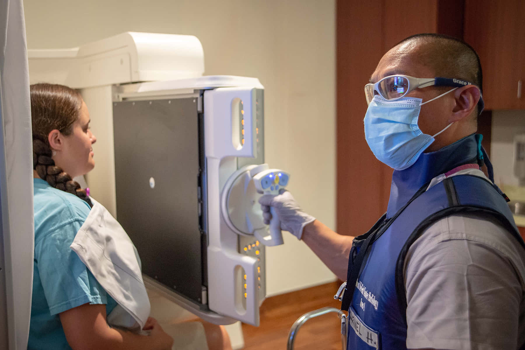 Unaenfermera Usando Una Máscara Y Guantes Está Examinando Una Máquina De Rayos X.