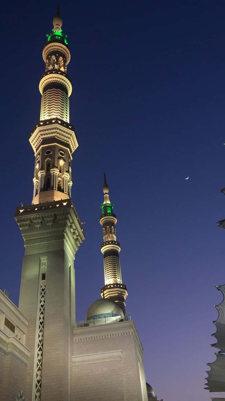A Mosque With Two Towers Lit Up At Night
