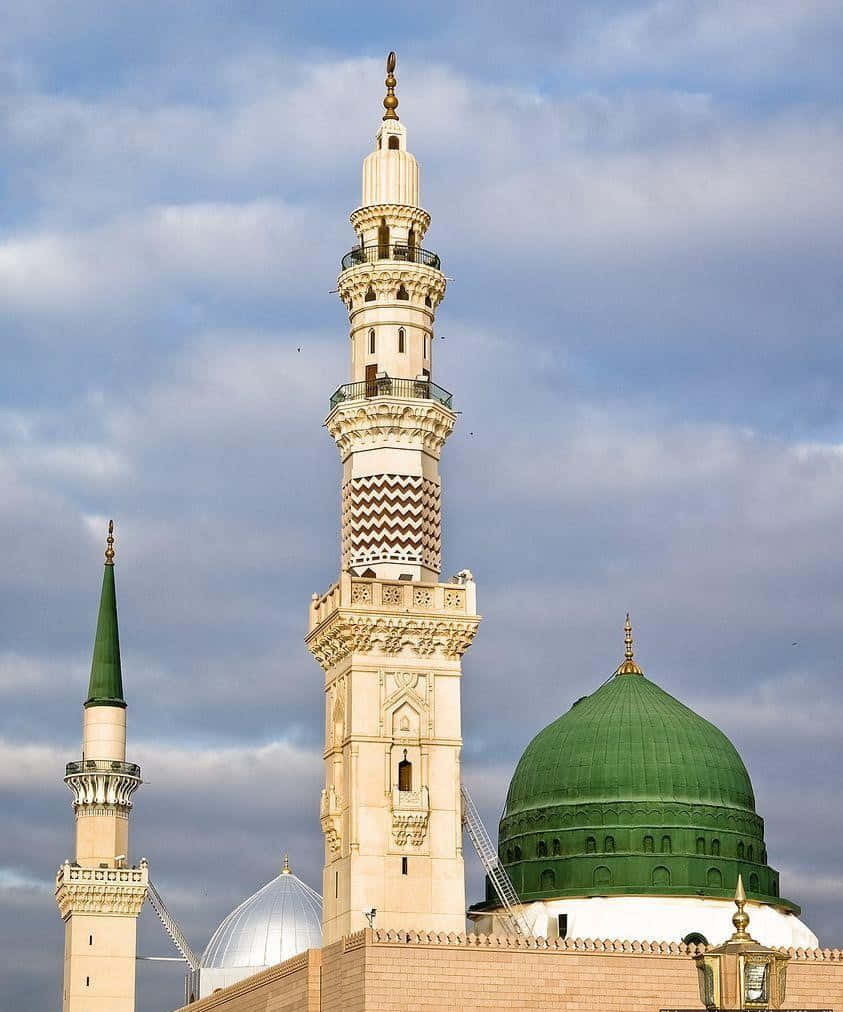 A Mosque With Two Green Domes And A Cloudy Sky