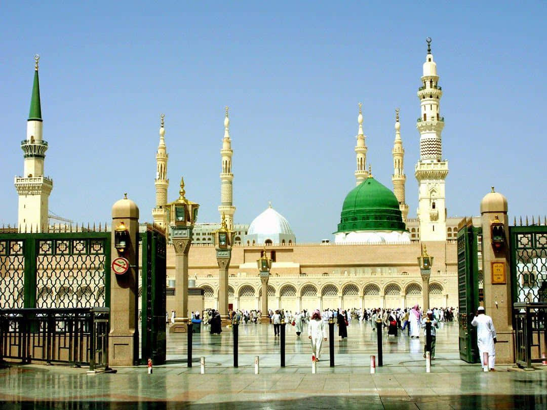 A Mosque With Green Domes And People Walking Around