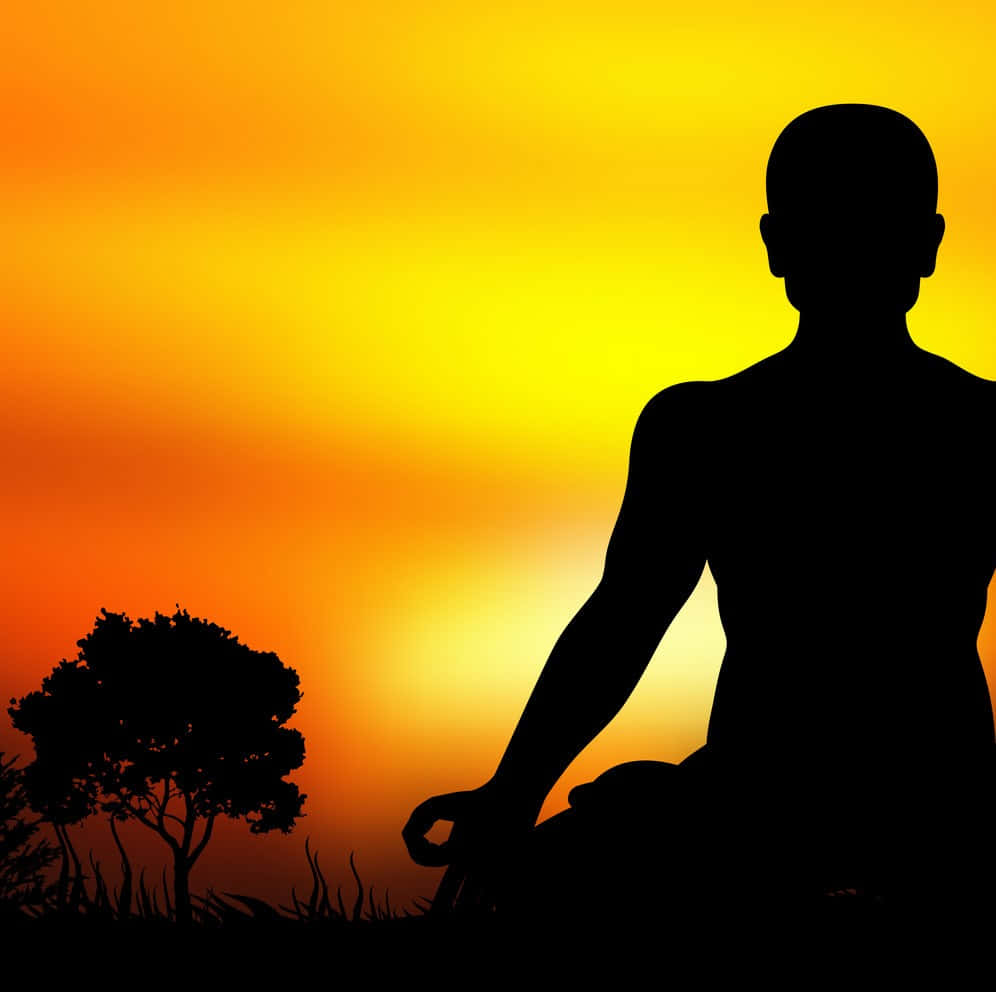 A Man Is Sitting In A Lotus Position At Sunset