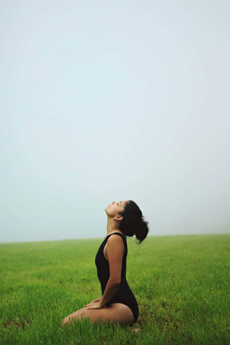 Kvinde, der mediterer på græsgrønt billede