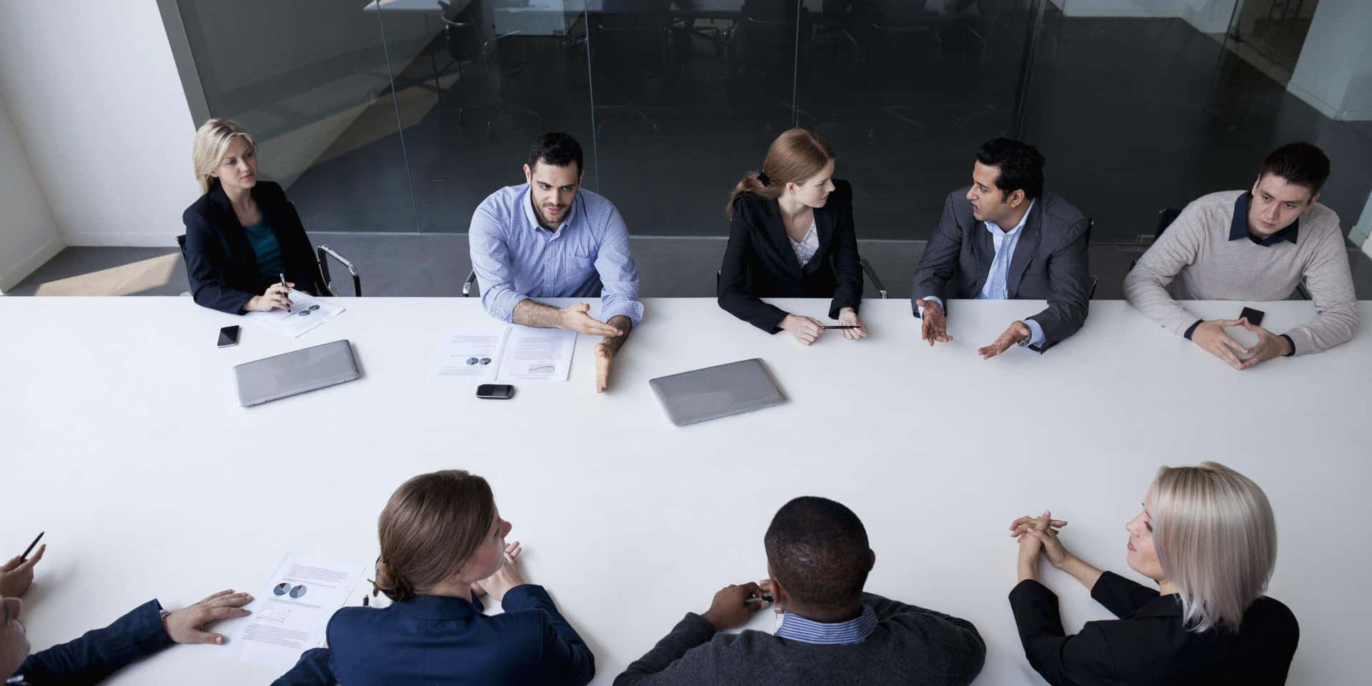 A Group Of People Sitting Around A Conference Table