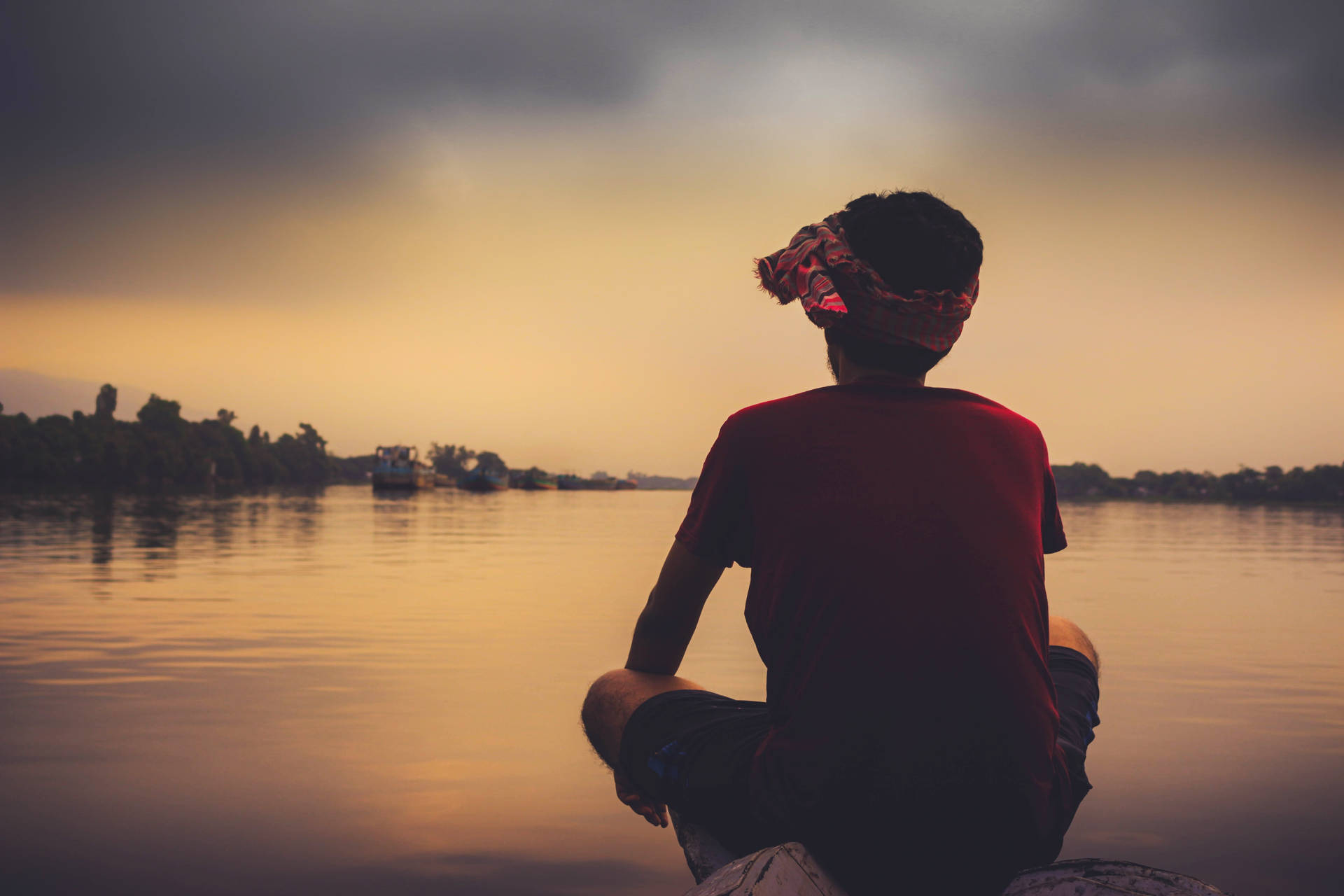 Melankolsk dreng ved søen ved morgenskumringen Wallpaper