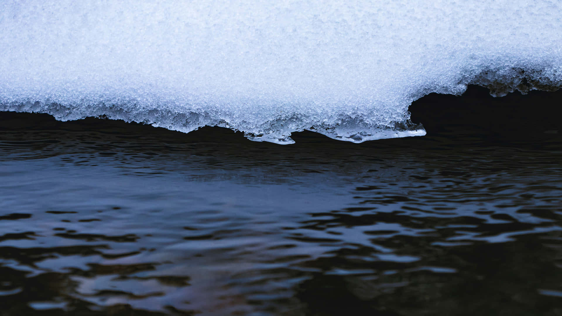 Melting Snow Edge Over Dark Water.jpg Wallpaper