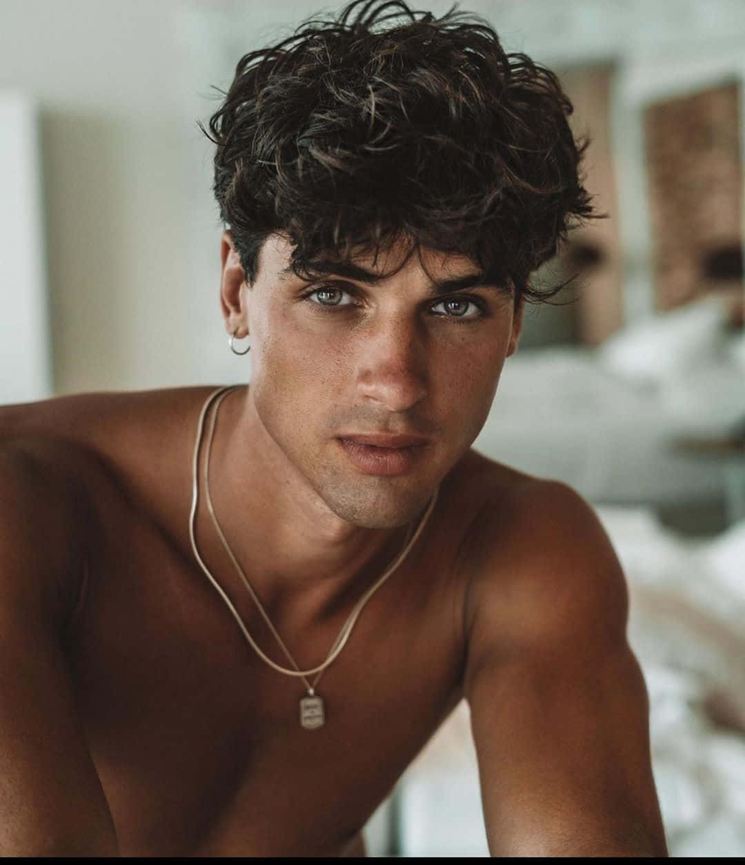 A Shirtless Man With Curly Hair Posing For A Photo