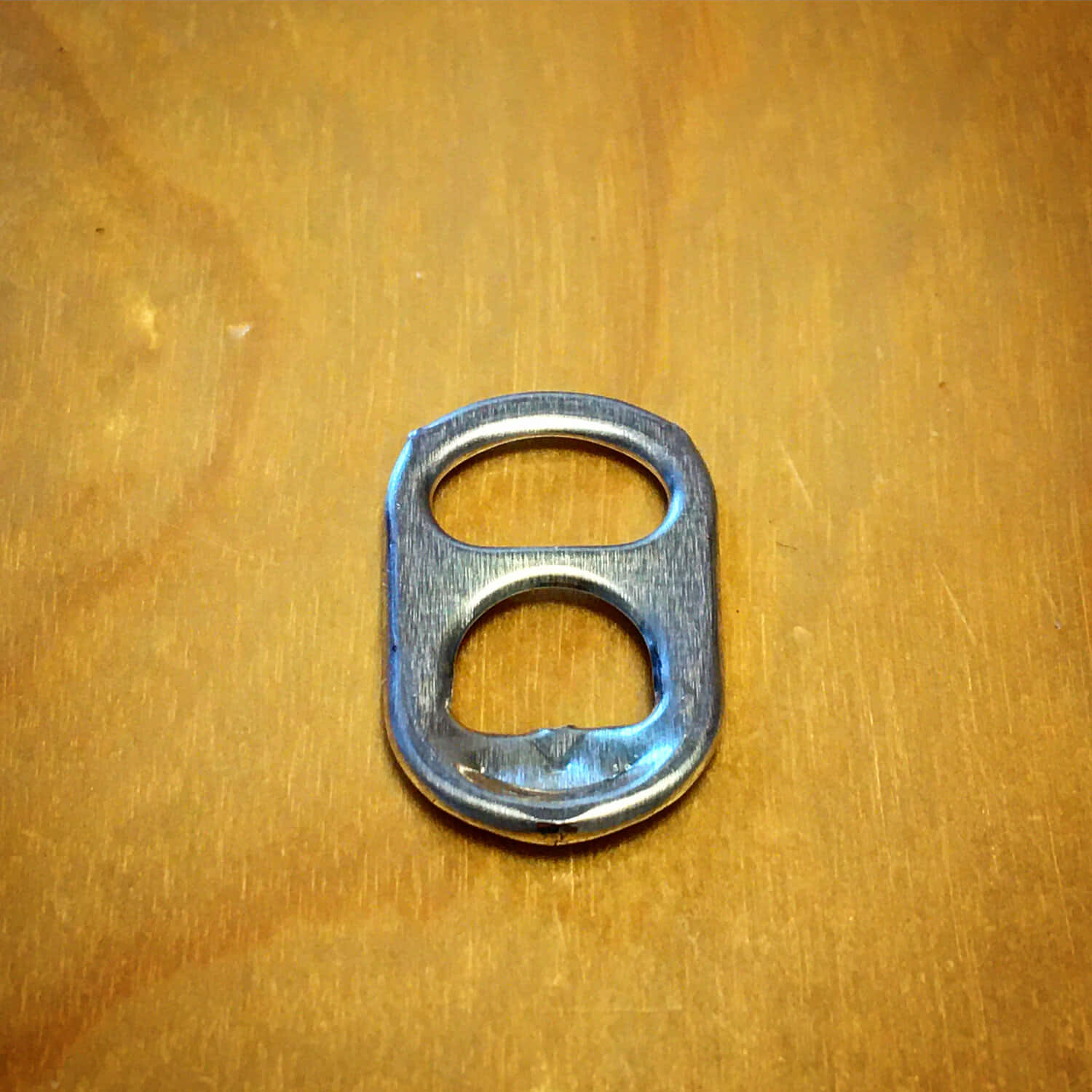 A Metal Bottle Opener On A Wooden Surface