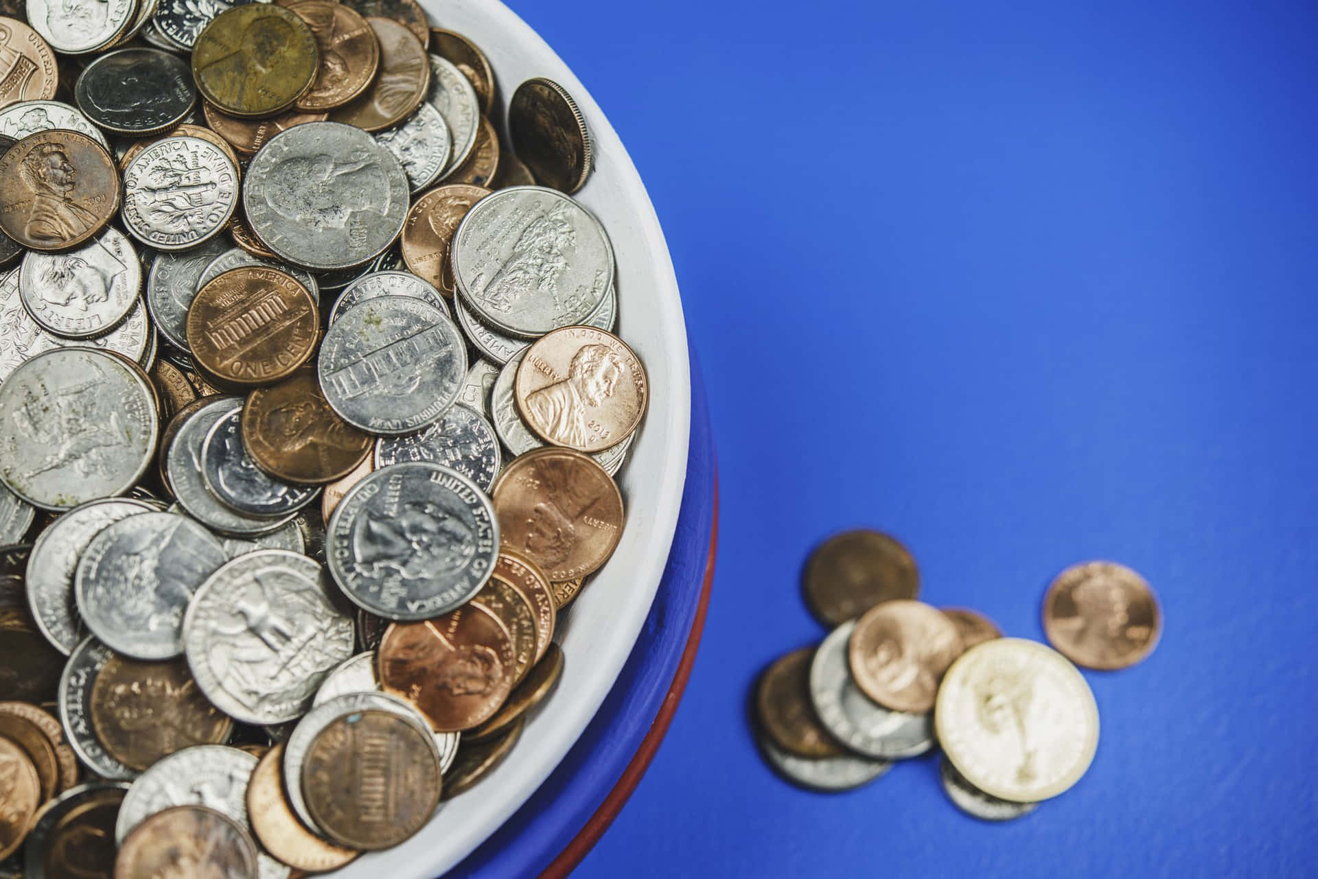 A Bowl Of Coins On A Blue Background