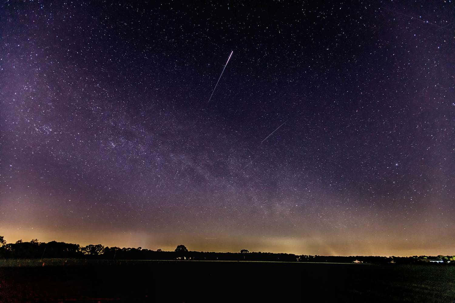 Reflektionav En Meteor Som Rusar Genom En Stjärnprydd Himmel.