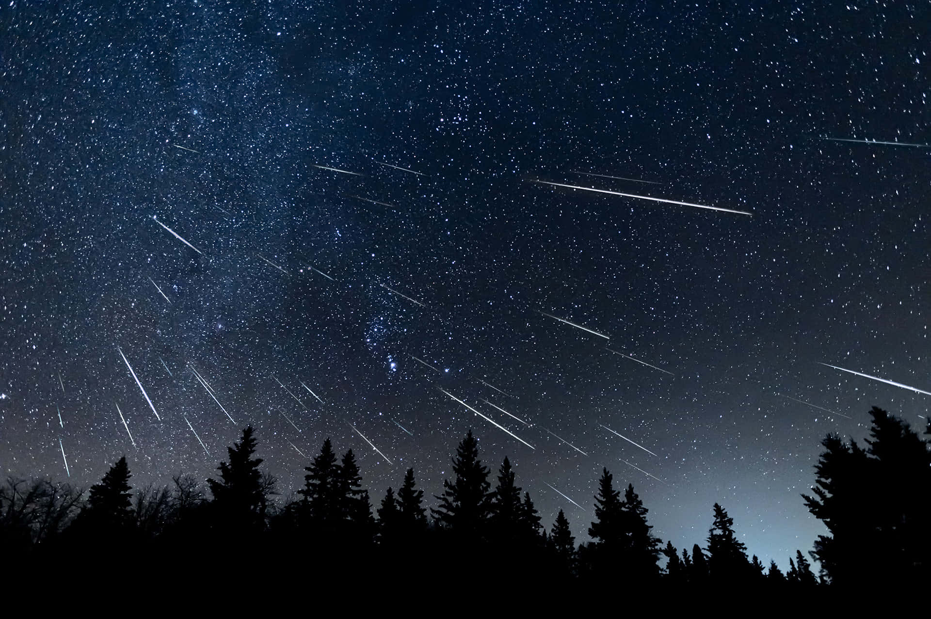 A brilliant meteor streaks across a cloudy night sky