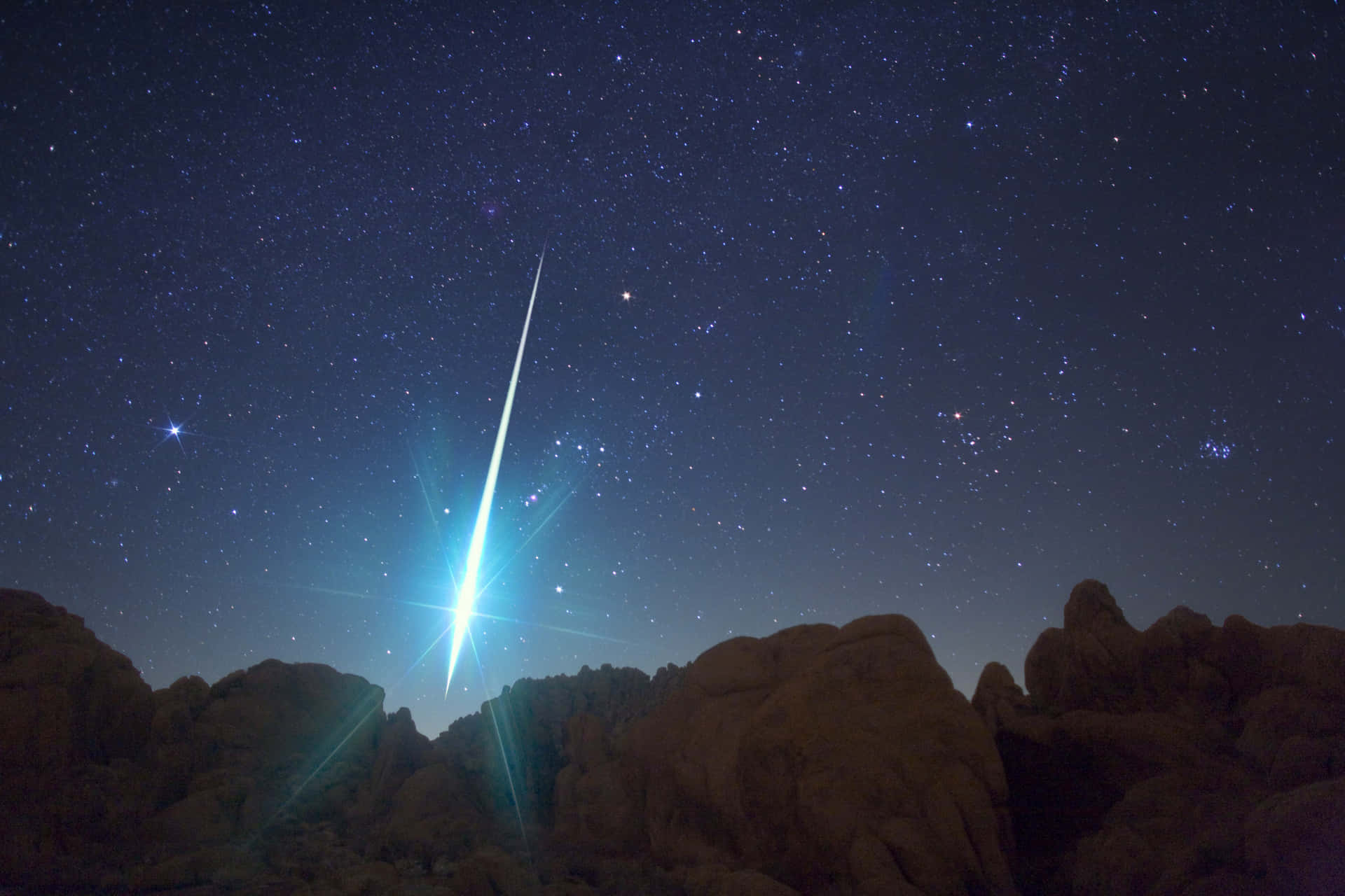 A bright meteor streaks across the night sky