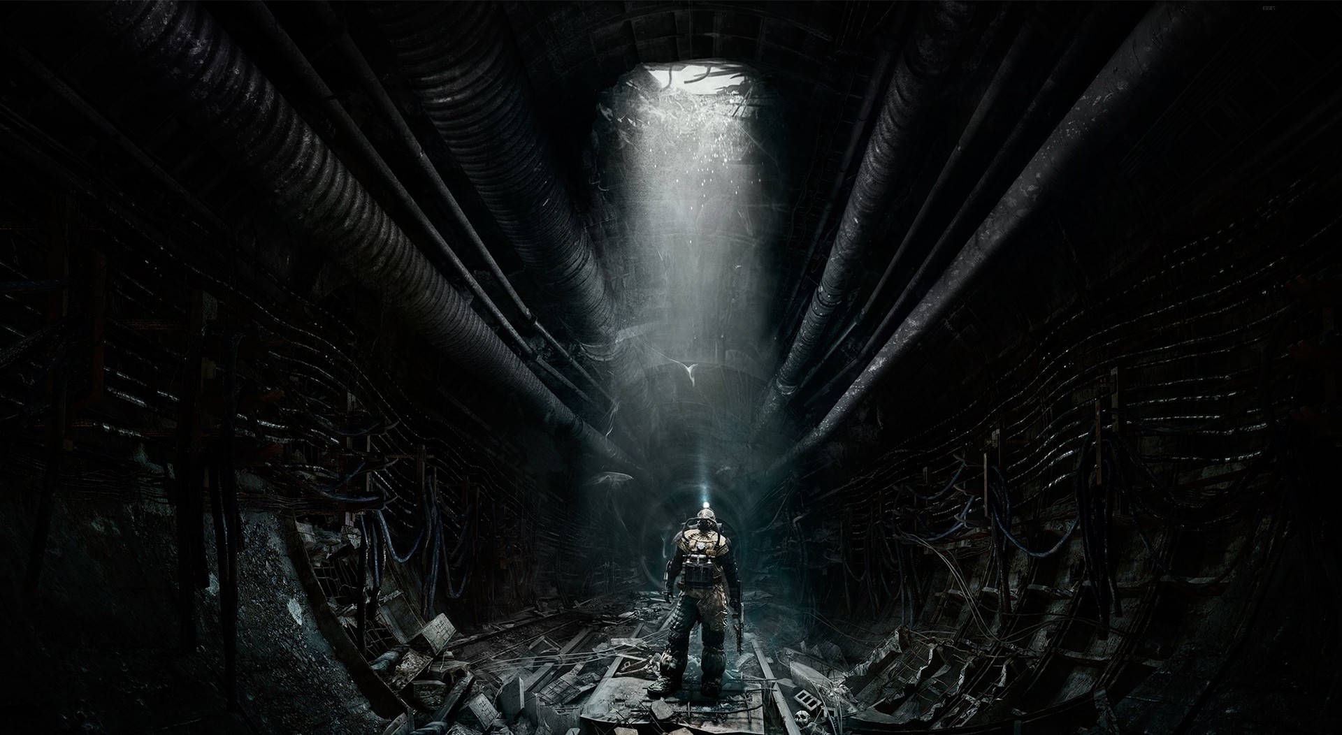 En mand står i en mørk tunnel med et lys, der skinner igennem. Wallpaper