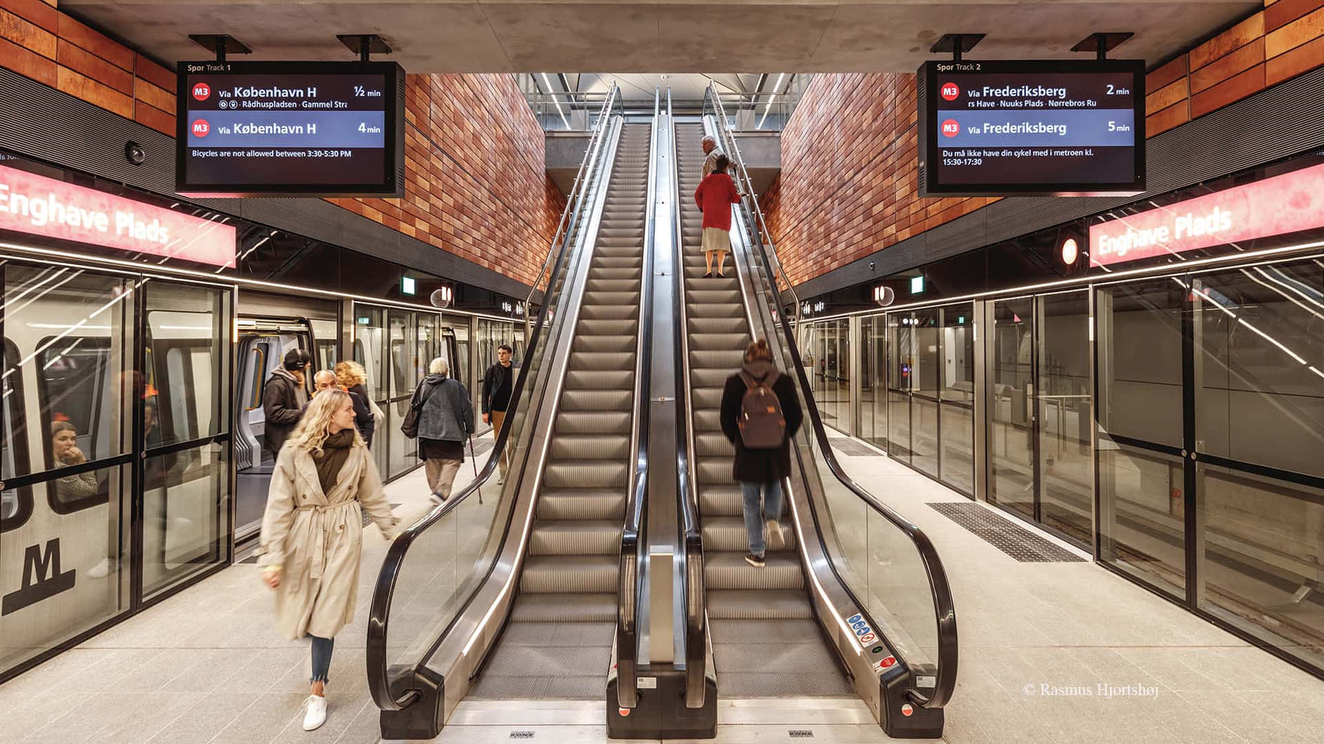 A Subway Station With Escalators And People Walking Down Them