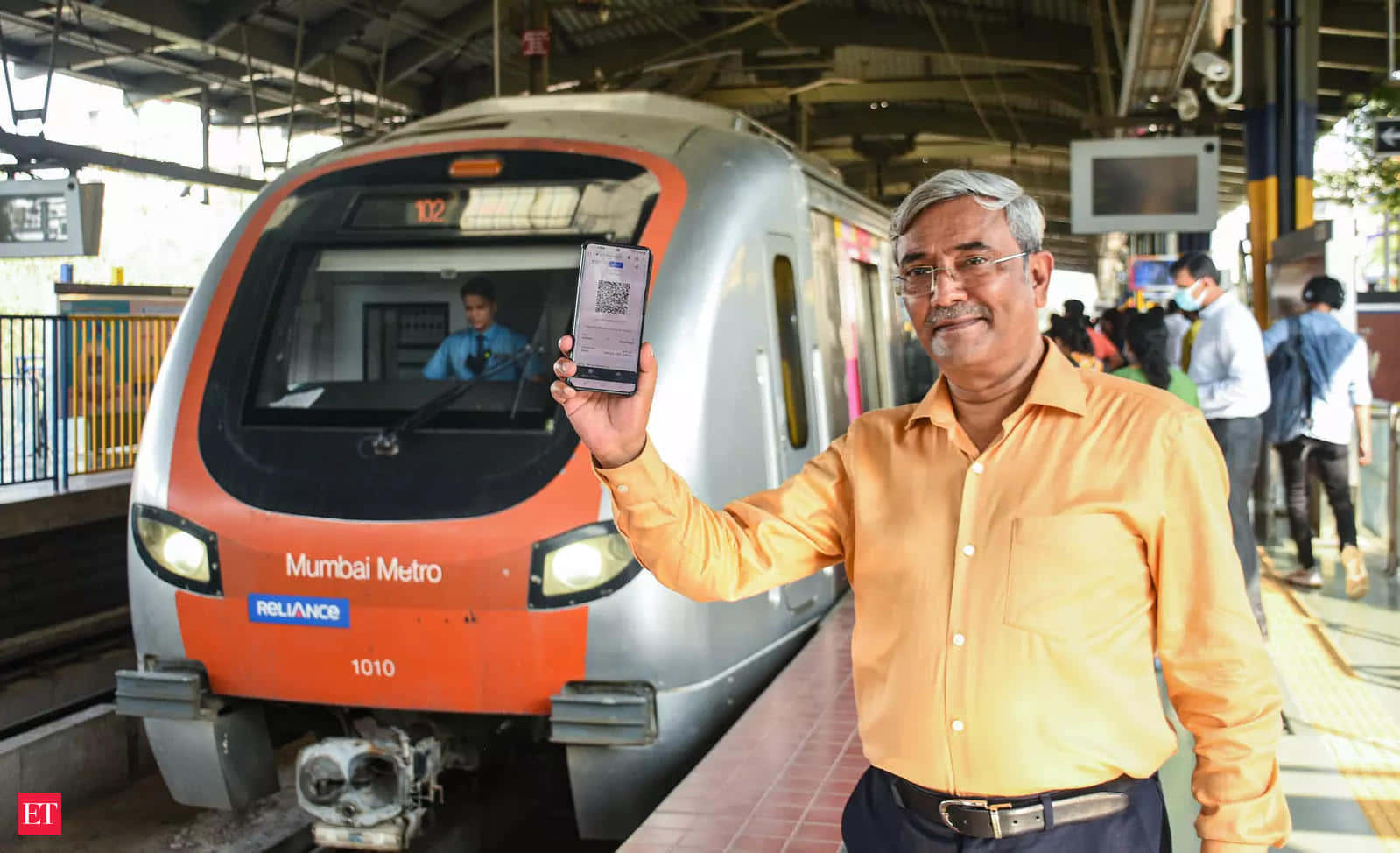 A Man Standing Next To A Train With His Phone