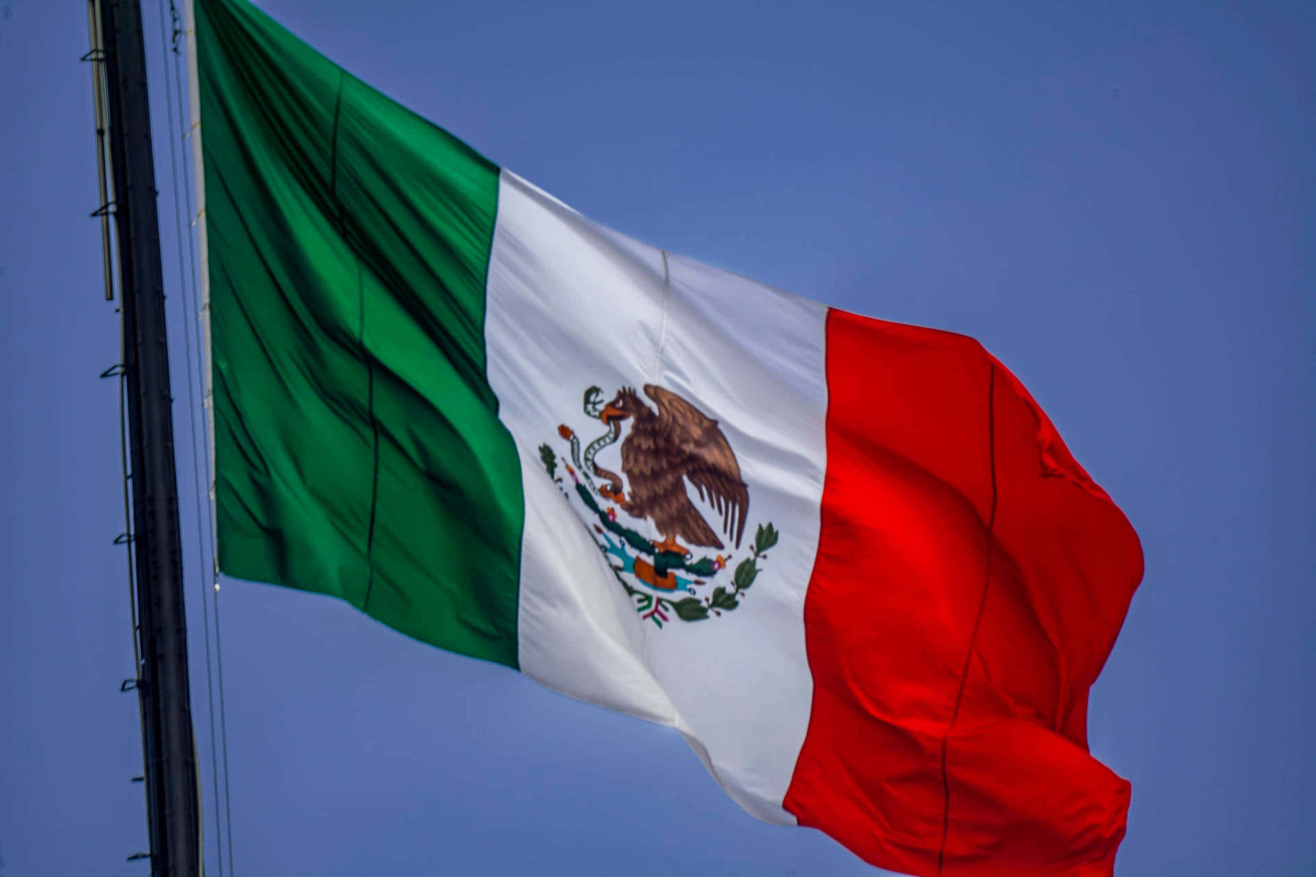Mexican Flag Waving Against Blue Sky Wallpaper