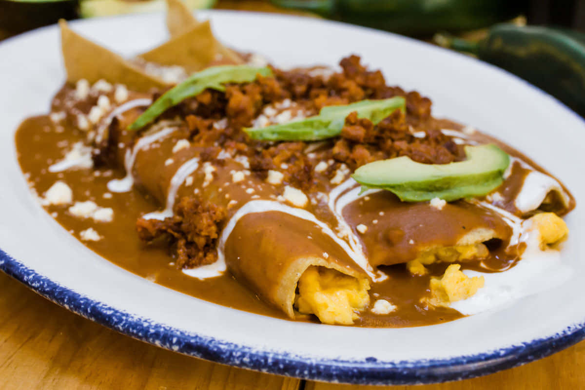 A Plate Of Enchiladas With Sauce And Tortillas
